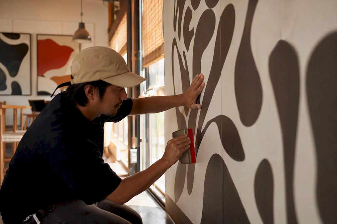 Hands smoothing wallpaper onto commercial wall