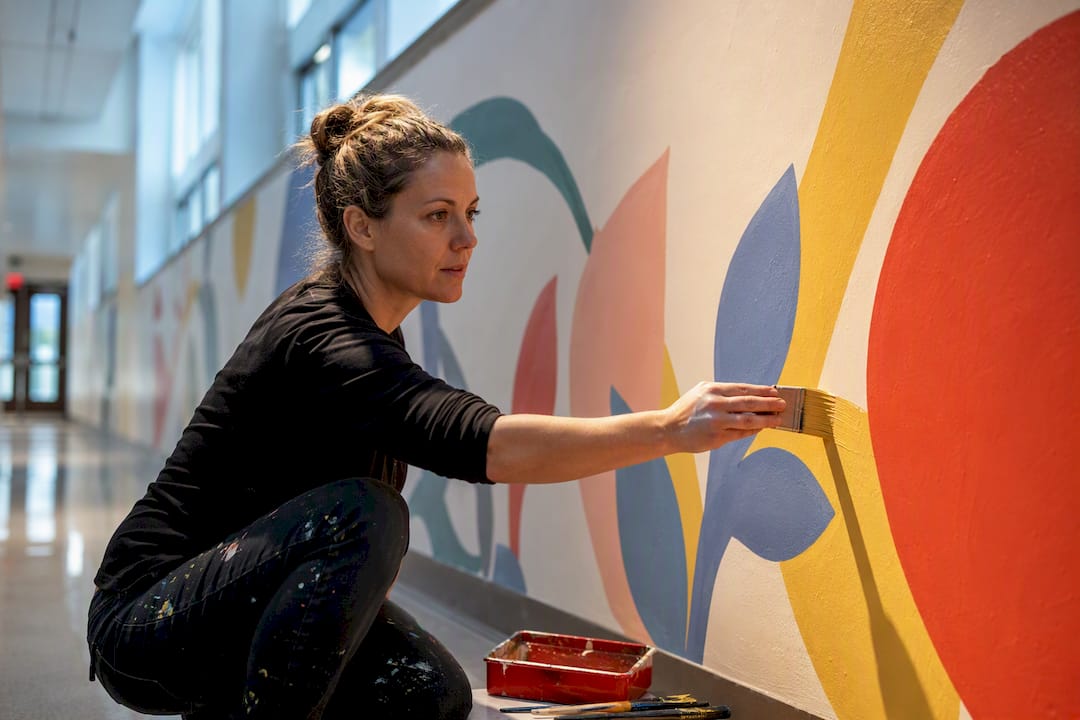 Teacher painting a colorful school hallway mural